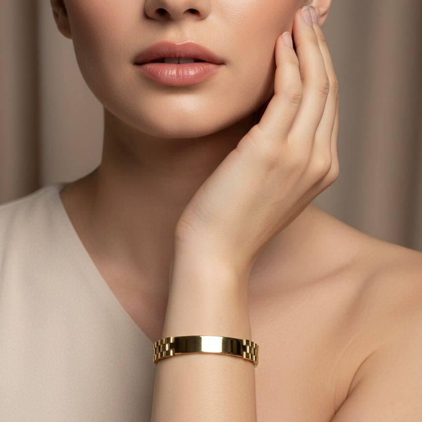 Woman wearing a gold bracelet on a neutral background