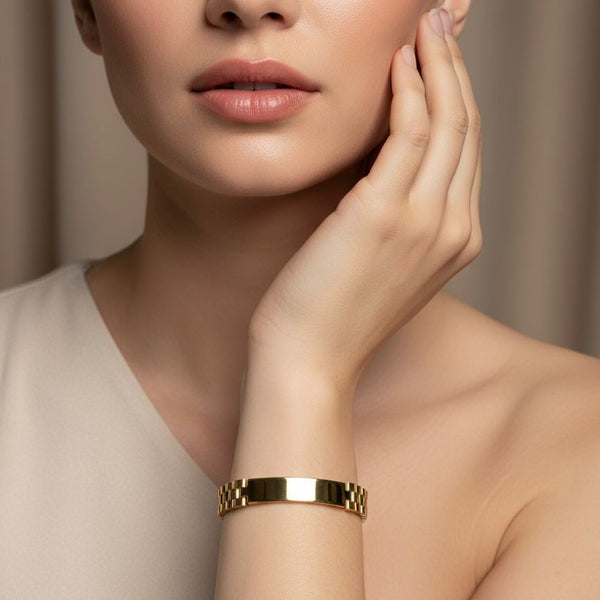Woman wearing a gold bracelet on a neutral background
